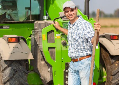 Portrait of a smiling farmer holding a pitchfork while working in his fieldの写真素材