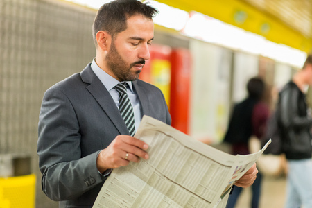 Commuter reading a newspaper while waiting for the subway trainの写真素材
