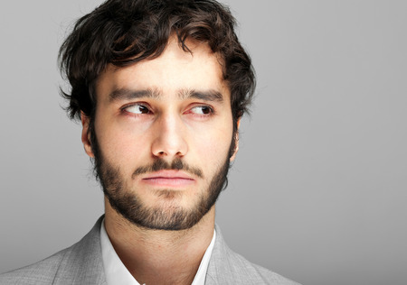 Thoughtful man against grey backgroundの写真素材