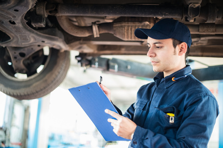 Portrait of a mechanic taking notes under a carの写真素材