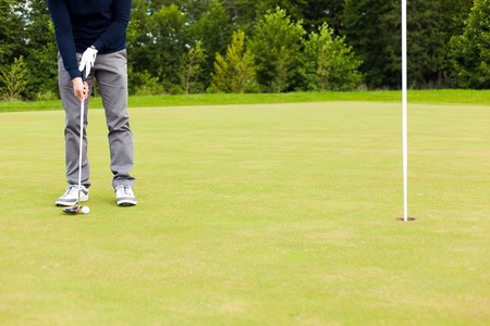 Male golf player drivers the ball into the holeの写真素材