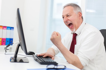 Very happy businessman looking at his computer monitorの写真素材