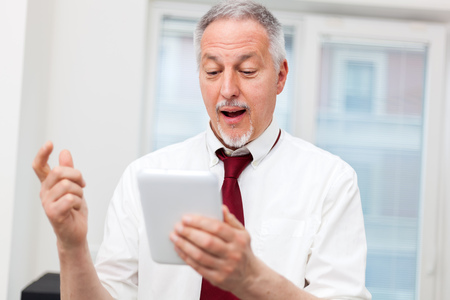 Satisfied businessman using his tablet in his officeの写真素材