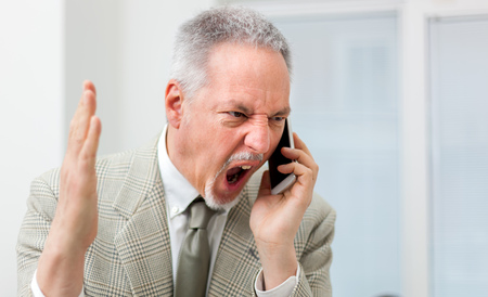 Angry businessman shouting on the phoneの写真素材