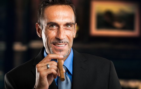Mature businessman smoking a cigar in a classy roomの写真素材
