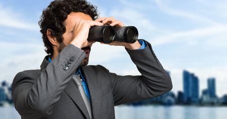 Businessman looking through binocularsの写真素材