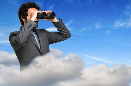 Businessman looking through binocularsの写真素材