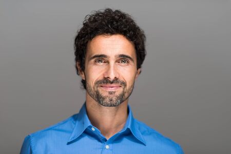 Closeup portrait of a happy young man smiling on gray backgroundの写真素材