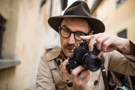 Spy or paparazzo photographer, man using camera in a city streetの写真素材