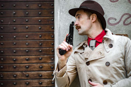 Detective taking cover and aiming with his handgunの写真素材
