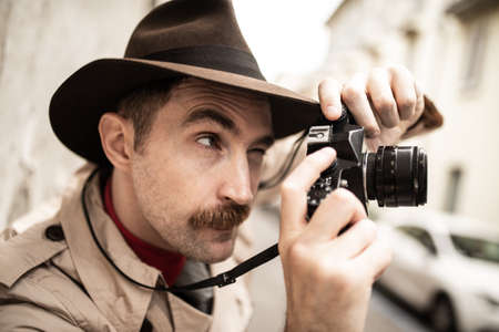 Spy or paparazzo photographer, man using camera in a city streetの写真素材