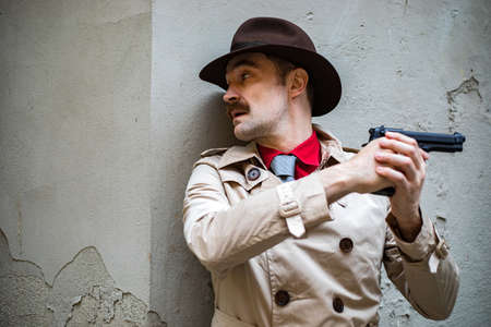 Detective taking cover and aiming with his handgunの写真素材