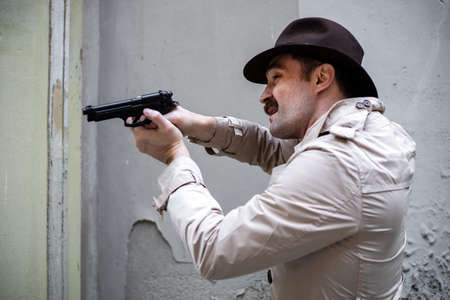 Detective taking cover and aiming with his handgunの写真素材
