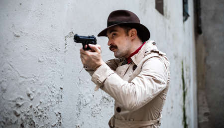 Detective taking cover and aiming with his handgunの写真素材