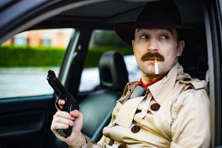 Detective readying his gun while waiting in his carの写真素材