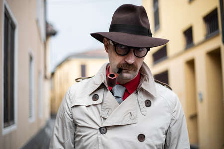 Vintage detective smoking a pipe outdoor in a grungy environmentの写真素材