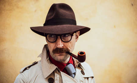 Vintage detective smoking a pipe outdoor in a grungy environmentの写真素材
