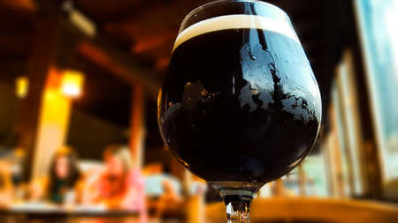 Glass of fresh dark beer on rustic pub backgroundの写真素材