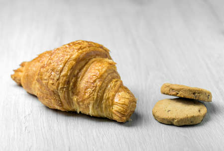 Freshly plain croissant on a bright wooden surfaceの写真素材