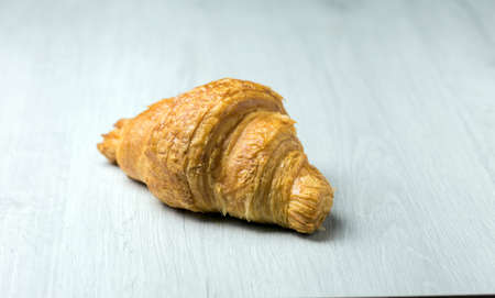 Freshly plain croissant on a bright wooden surfaceの写真素材