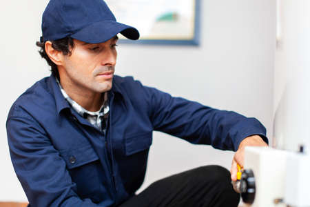 Smiling technician repairing an hot-water heaterの写真素材