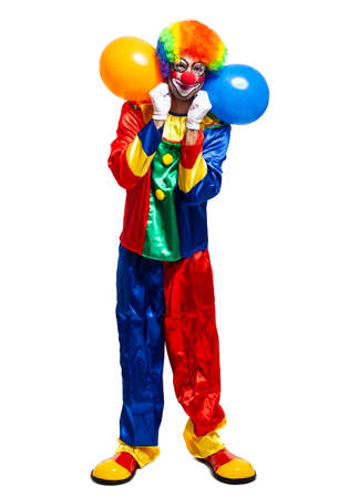 Full length portrait of a male clown in costume holding bunch of balloons isolated on white backgroundの写真素材