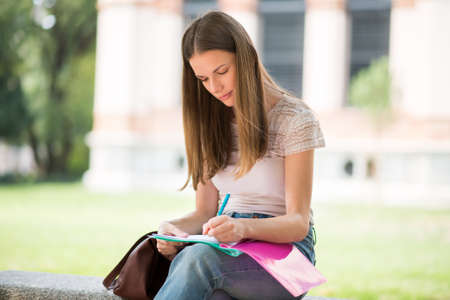 Portrait of a female student studying in a park in front of the schoolの写真素材