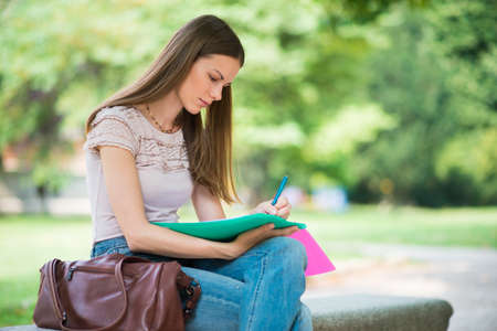 Portrait of a female student studying in a park in front of the schoolの写真素材
