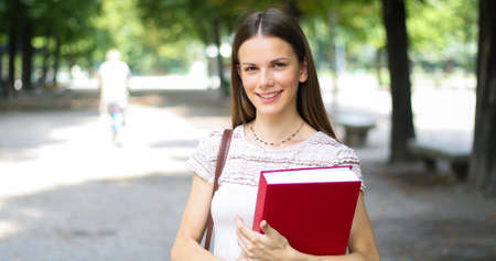 Portrait of a female student studying in a park in front of the schoolの写真素材
