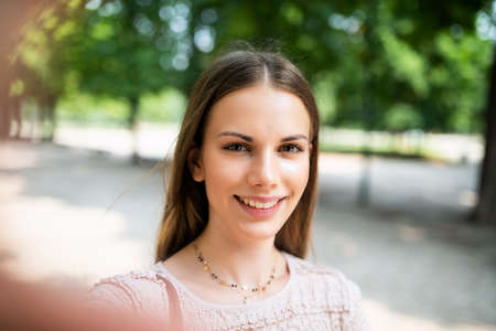 Portrait of a female student studying in a park in front of the schoolの写真素材