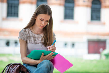 Portrait of a female student studying in a park in front of the schoolの写真素材