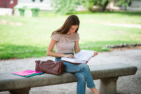 Portrait of a female student studying in a park in front of the schoolの写真素材