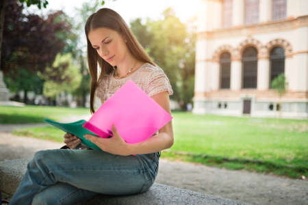 Portrait of a female student studying in a park in front of the schoolの写真素材