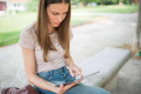 Portrait of a female student studying in a park in front of the schoolの写真素材