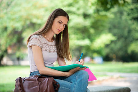 Portrait of a female student studying in a park in front of the schoolの写真素材