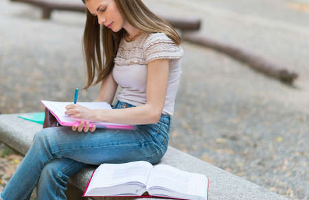 Portrait of a female student studying in a park in front of the schoolの写真素材