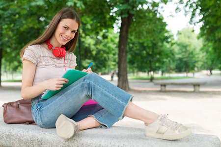 Portrait of a female student studying in a park in front of the schoolの写真素材