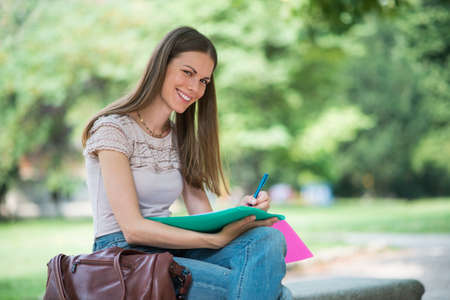 Portrait of a female student studying in a park in front of the schoolの写真素材