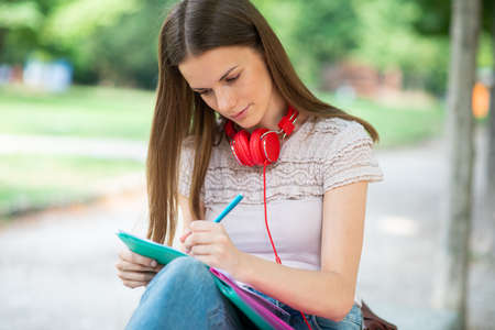 Portrait of a female student studying in a park in front of the schoolの写真素材
