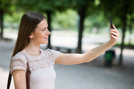 Portrait of a female student studying in a park in front of the schoolの写真素材