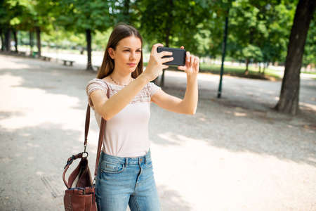 Young woman using her mobile phone to take a photoの写真素材
