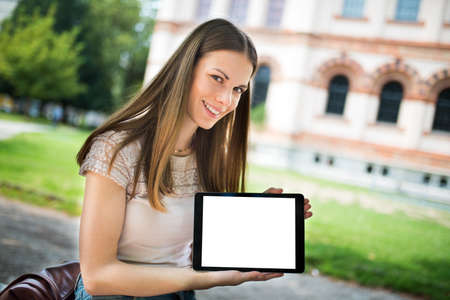 Young happy woman showing an empty tablet screenの写真素材