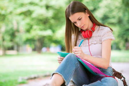 Portrait of a female student studying in a park in front of the schoolの写真素材