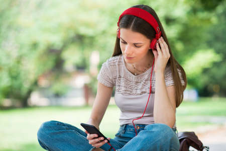 Smiling teenager listening music from her phoneの写真素材