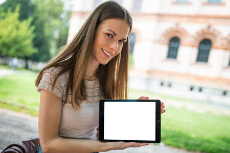 Young smiling woman showing an empty tablet screenの写真素材
