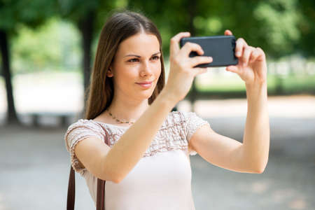 Young woman using her mobile phone to take a photoの写真素材