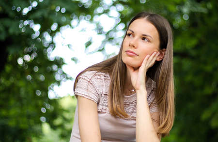 portrait of a pretty thoughtful lady sitting on a banch in a parkの写真素材