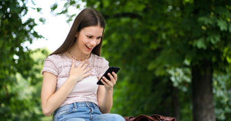 Very happy woman reading good news via her smartphoneの写真素材