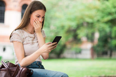 Surprised woman looking at her mobile phoneの写真素材
