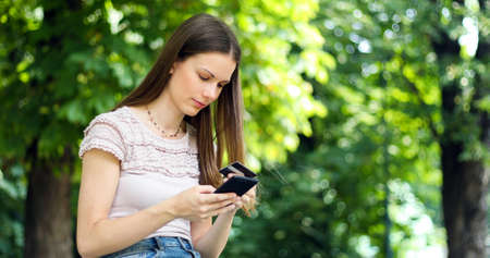 SPortrait of a happy woman paying online with credit card and smart phone in a parkの写真素材